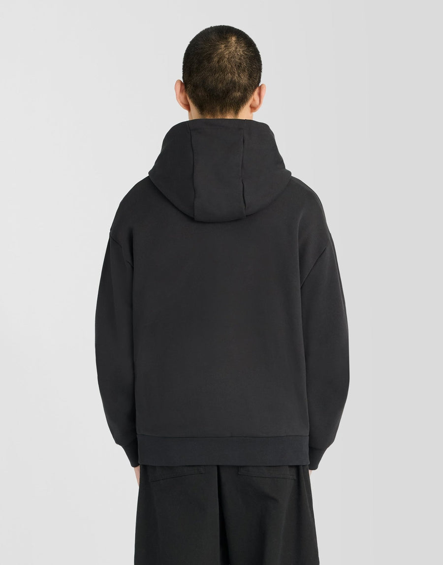 Man wears Heavyweight Loopback Zip Hoodie in Jet Black