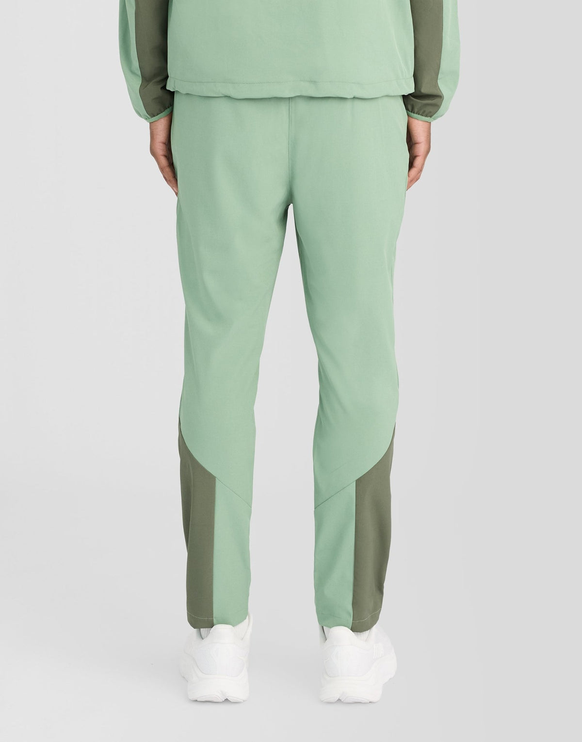 Man bär träningsbyxor med paneler i färgerna Botanical Green/Cactus Green