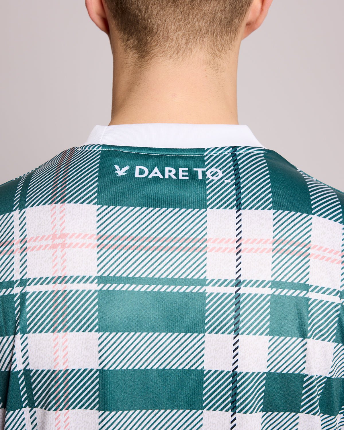 Un homme porte un maillot de football à carreaux tartan de sport, couleur Everglade