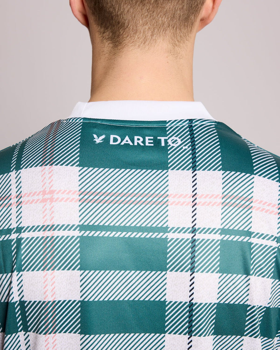 Un homme porte un maillot de football à carreaux tartan de sport, couleur Everglade