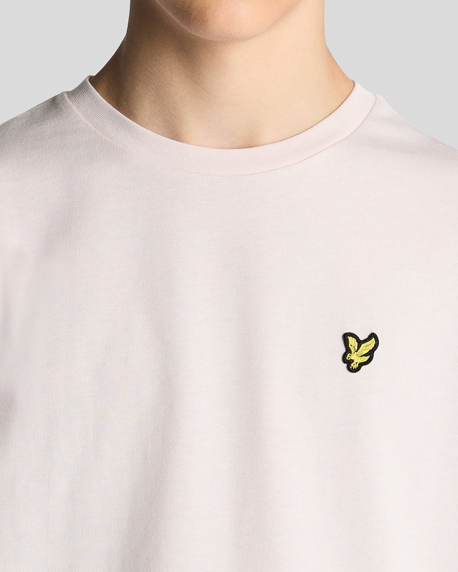 Un homme porte un t-shirt à col rond en coton rose pâle