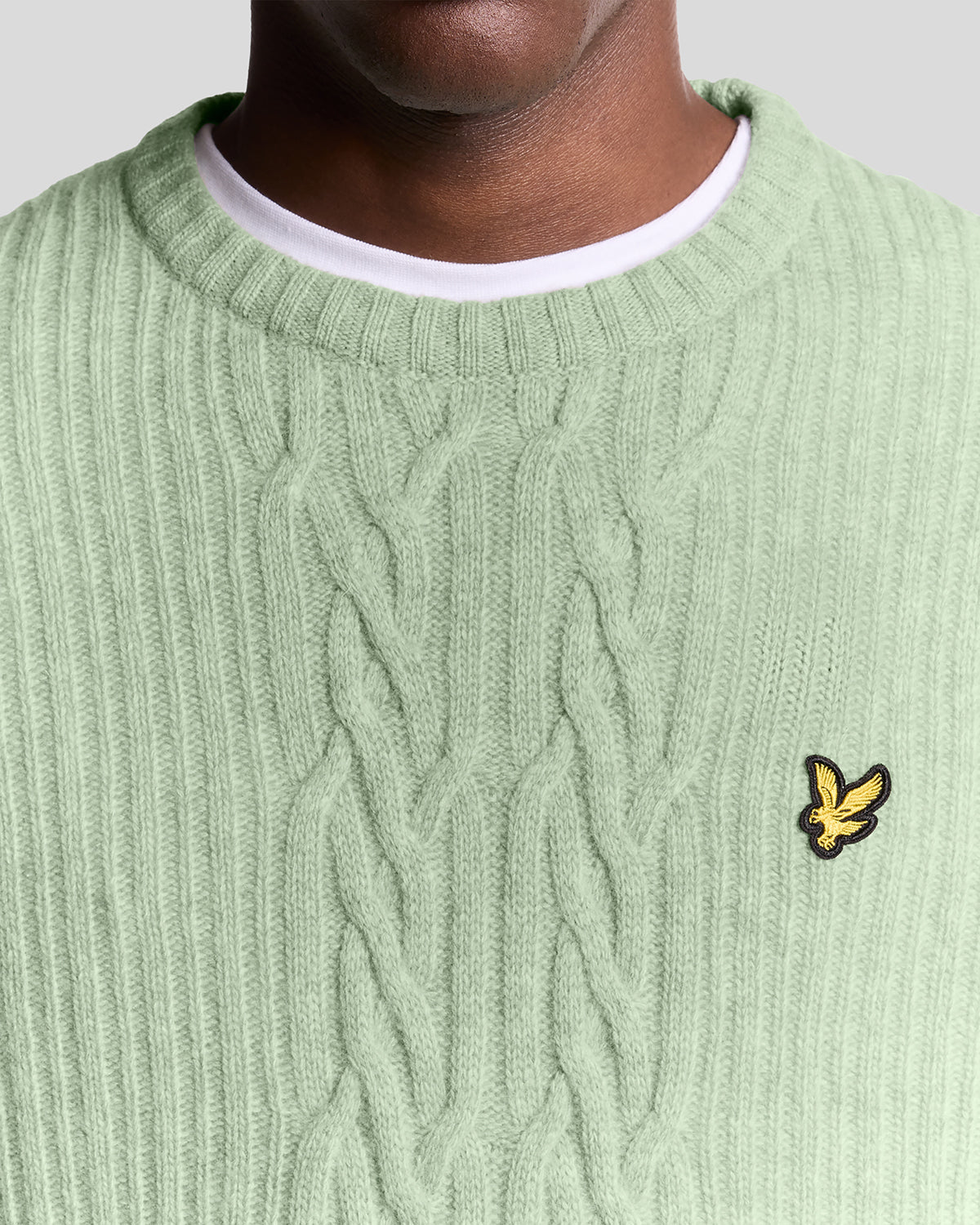 Un homme porte un pull en maille torsadée côtelée, couleur « Cold Mint Marl »
