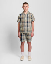 Man wears Linen Blend Check Shorts in Herb Green
