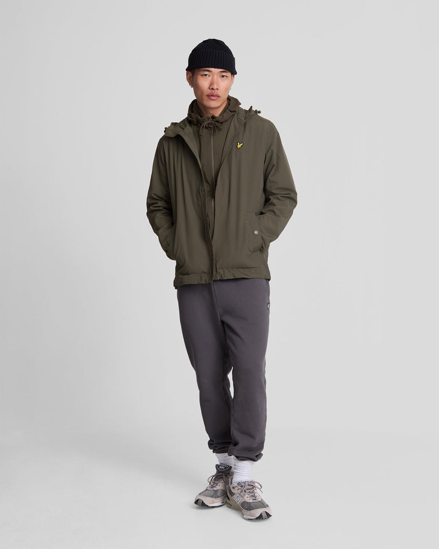 Un homme porte une veste à capuche imperméable de couleur olive
