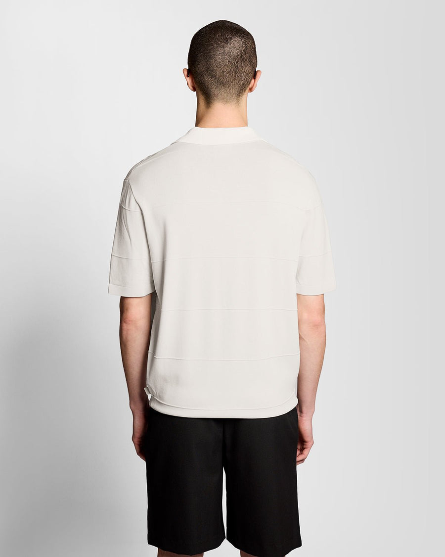 Un homme porte un polo en maille fine à col ouvert, couleur Skylight
