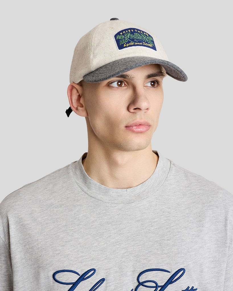Un homme porte une casquette à patch Wavey Garms de couleur crème
