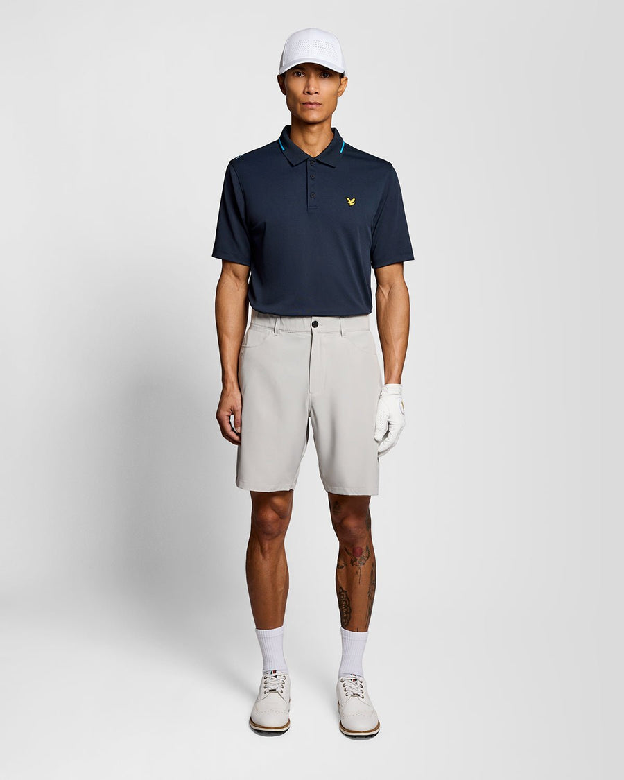 Un homme porte un polo technique à bordures contrastées bleu marine foncé