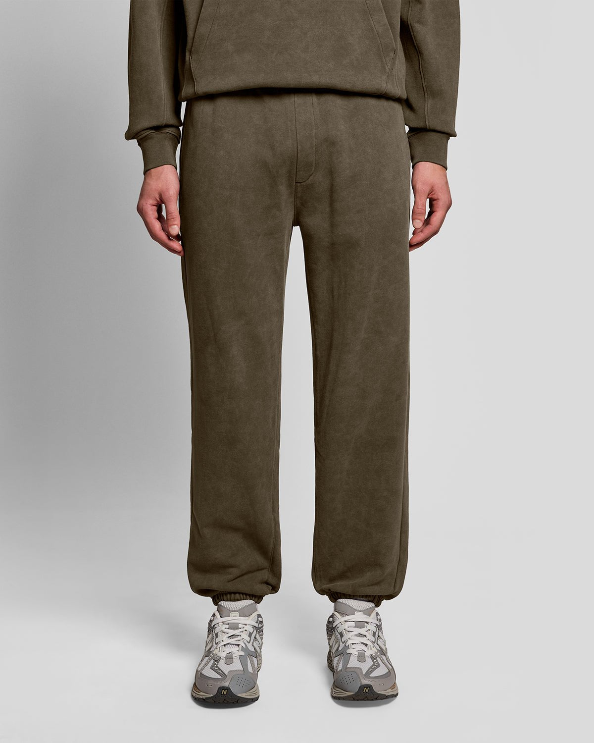 Un homme porte un pantalon de jogging en coton délavé foncé, couleur noir mat