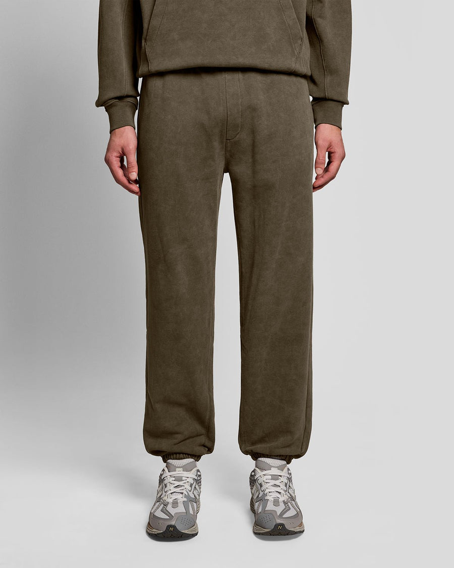 Un homme porte un pantalon de jogging en coton délavé foncé, couleur noir mat
