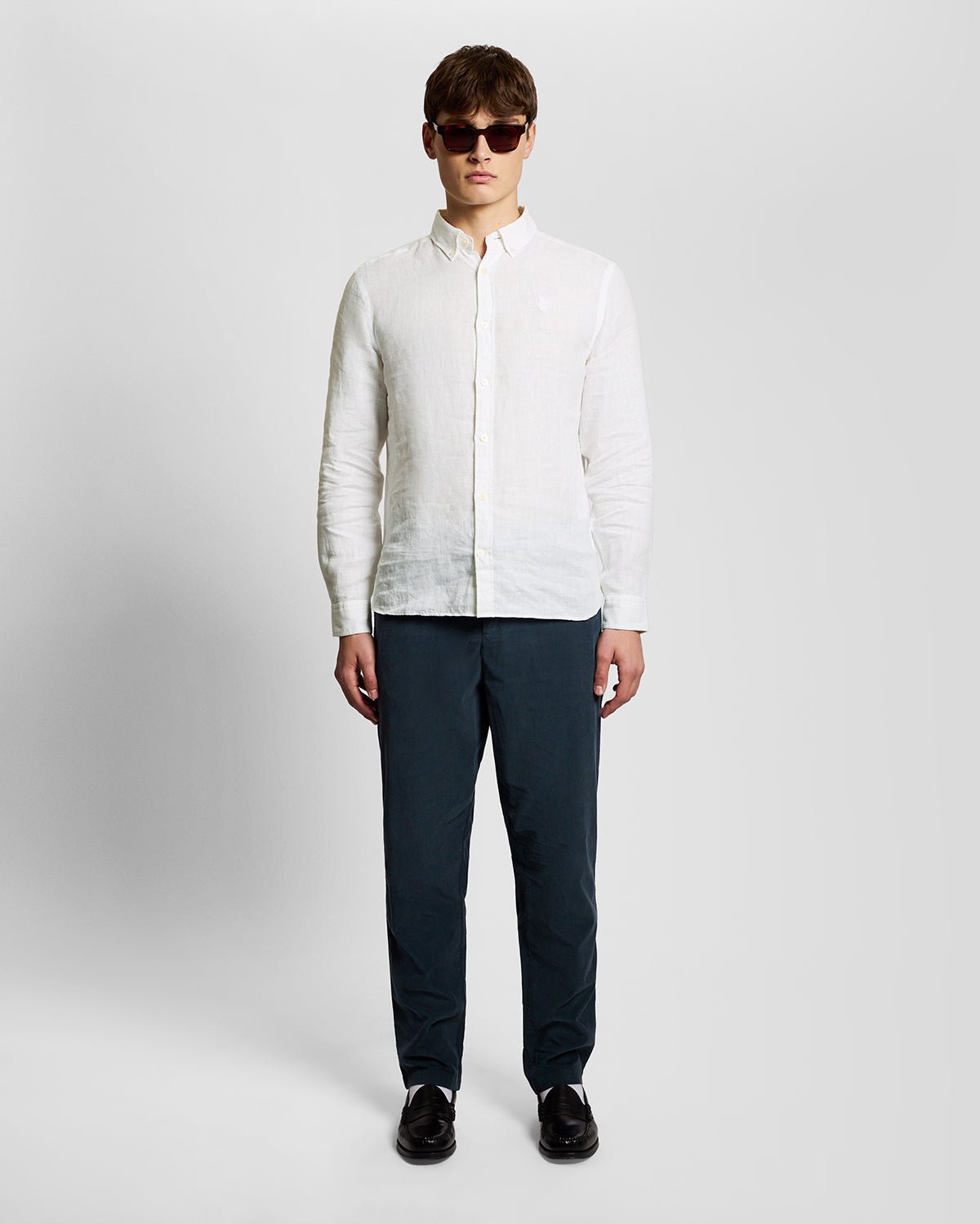 Un homme porte une chemise en lin boutonnée, de couleur blanche
