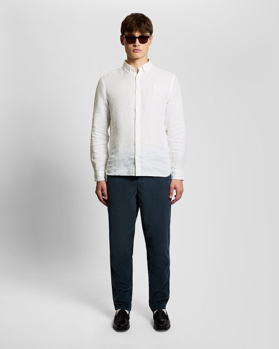 Un homme porte une chemise en lin boutonnée, de couleur blanche