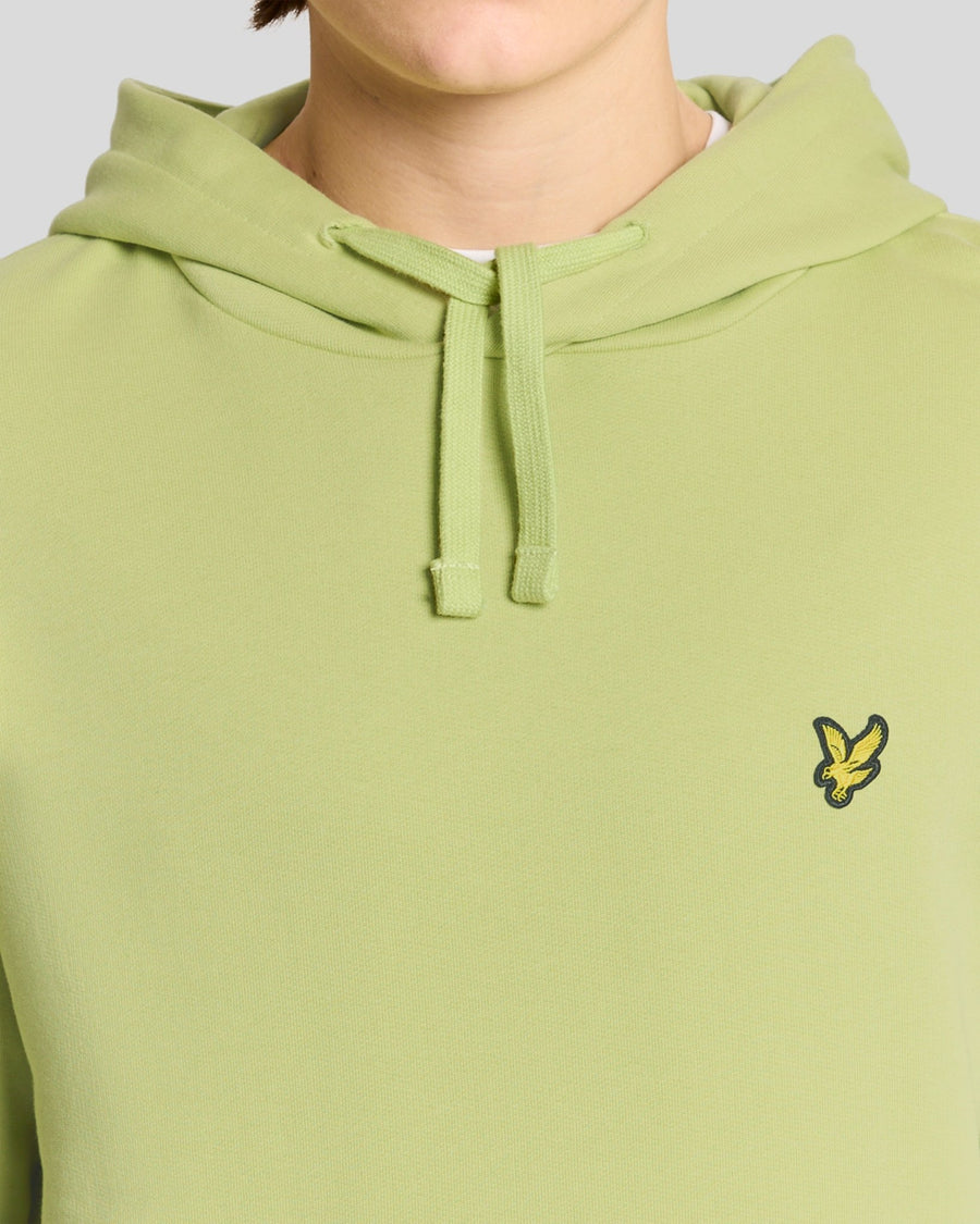Un homme porte un sweat à capuche Loopback en coton, couleur « Green Grass »