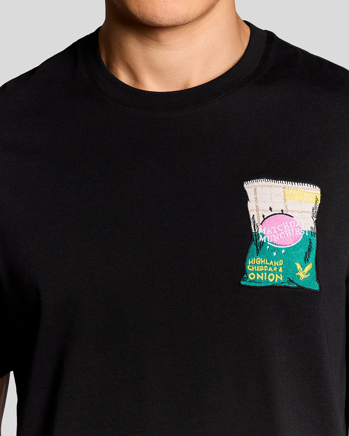 Homme portant un t-shirt à col rond avec motif brodé, couleur noir de jais