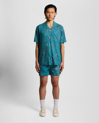 Man wears Goldfish Graphic Swim Shorts in Lagoon/ Orange Blaze
