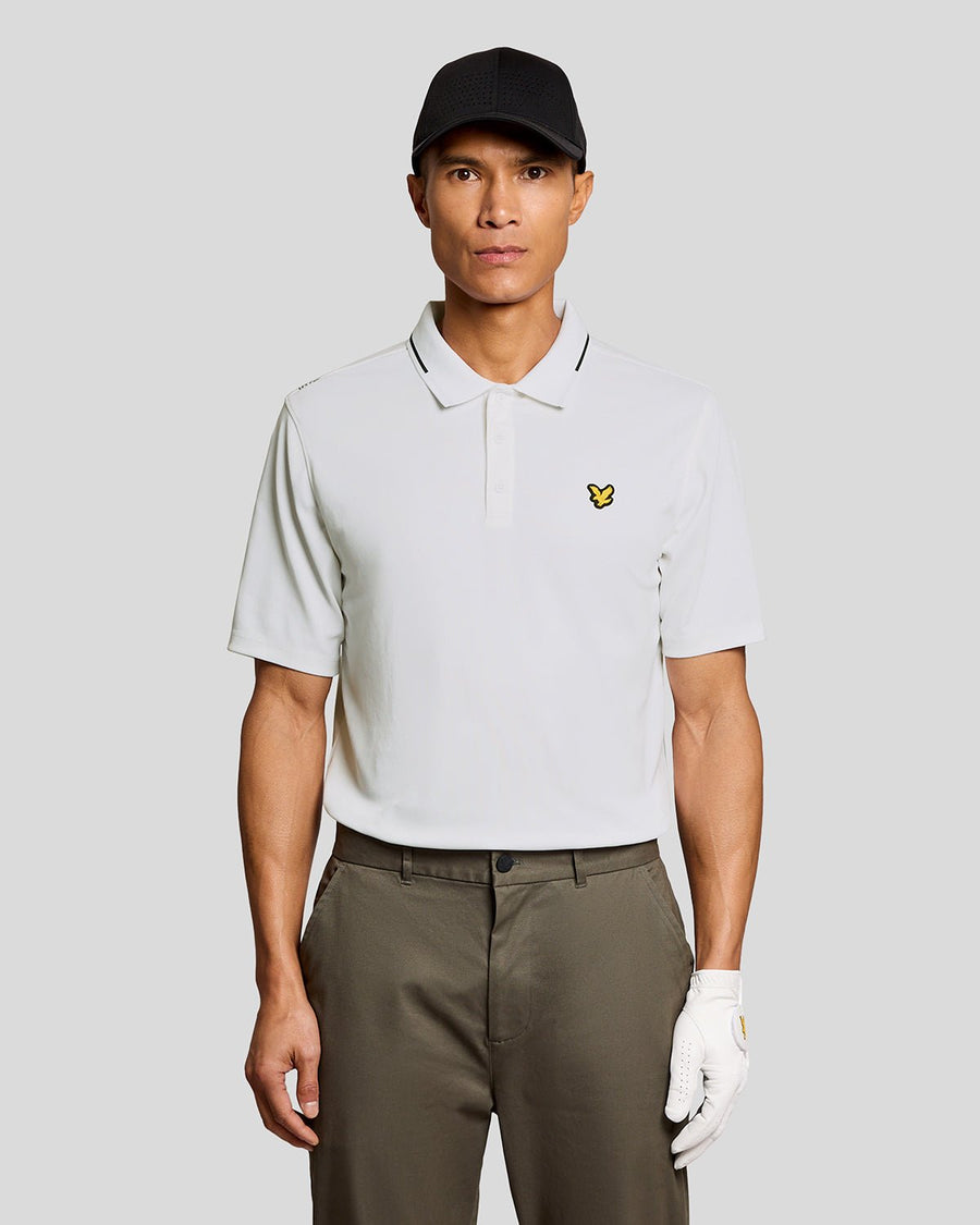 Un homme porte un polo technique à bordures contrastées, de couleur blanche