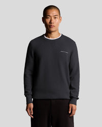 Man wears Knitted Script Crew Neck Jumper in Dark Navy
