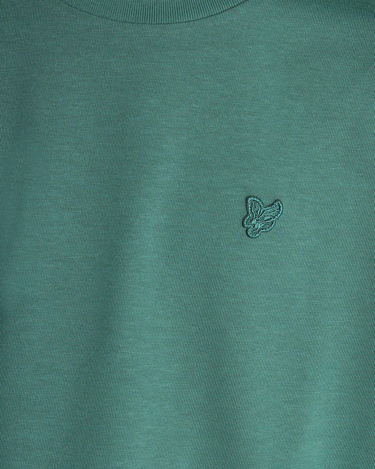 Un homme porte un t-shirt ample épais de couleur Everglade