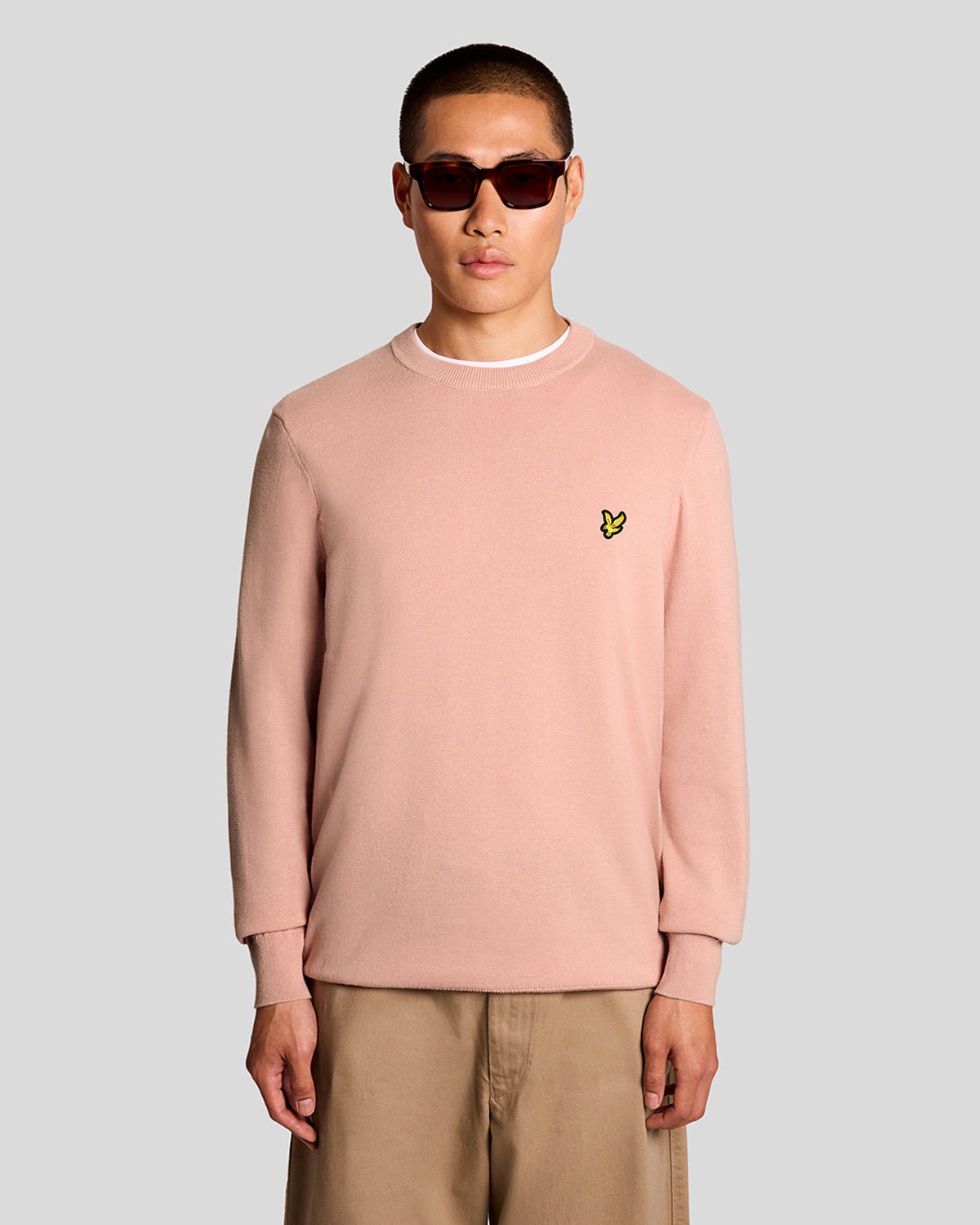 Homme portant un pull à col rond en coton couleur pamplemousse rose