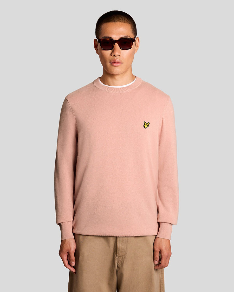 Homme portant un pull à col rond en coton couleur pamplemousse rose