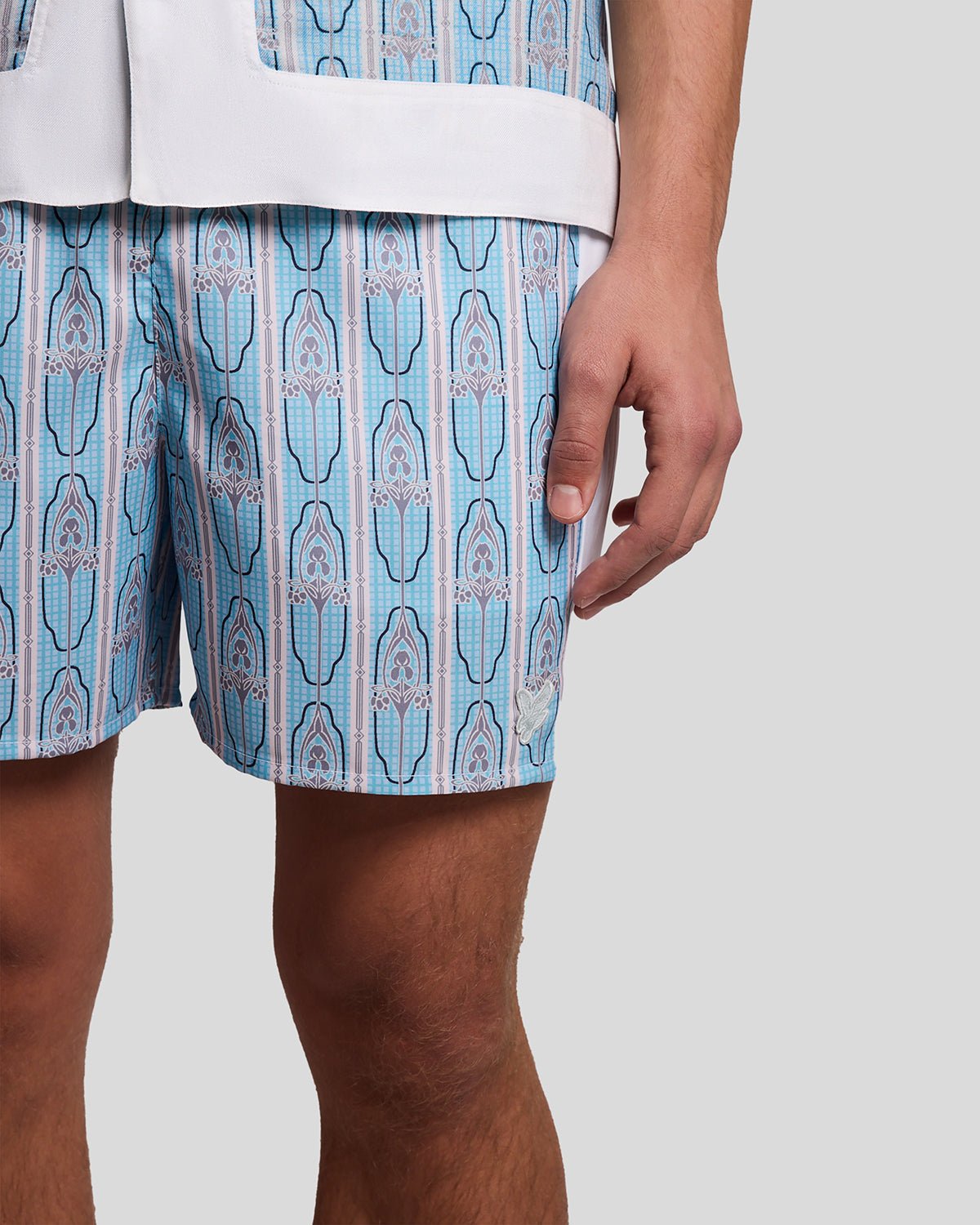 Homme portant un short de bain à motifs floraux, couleur crème amande/bleu de Parme