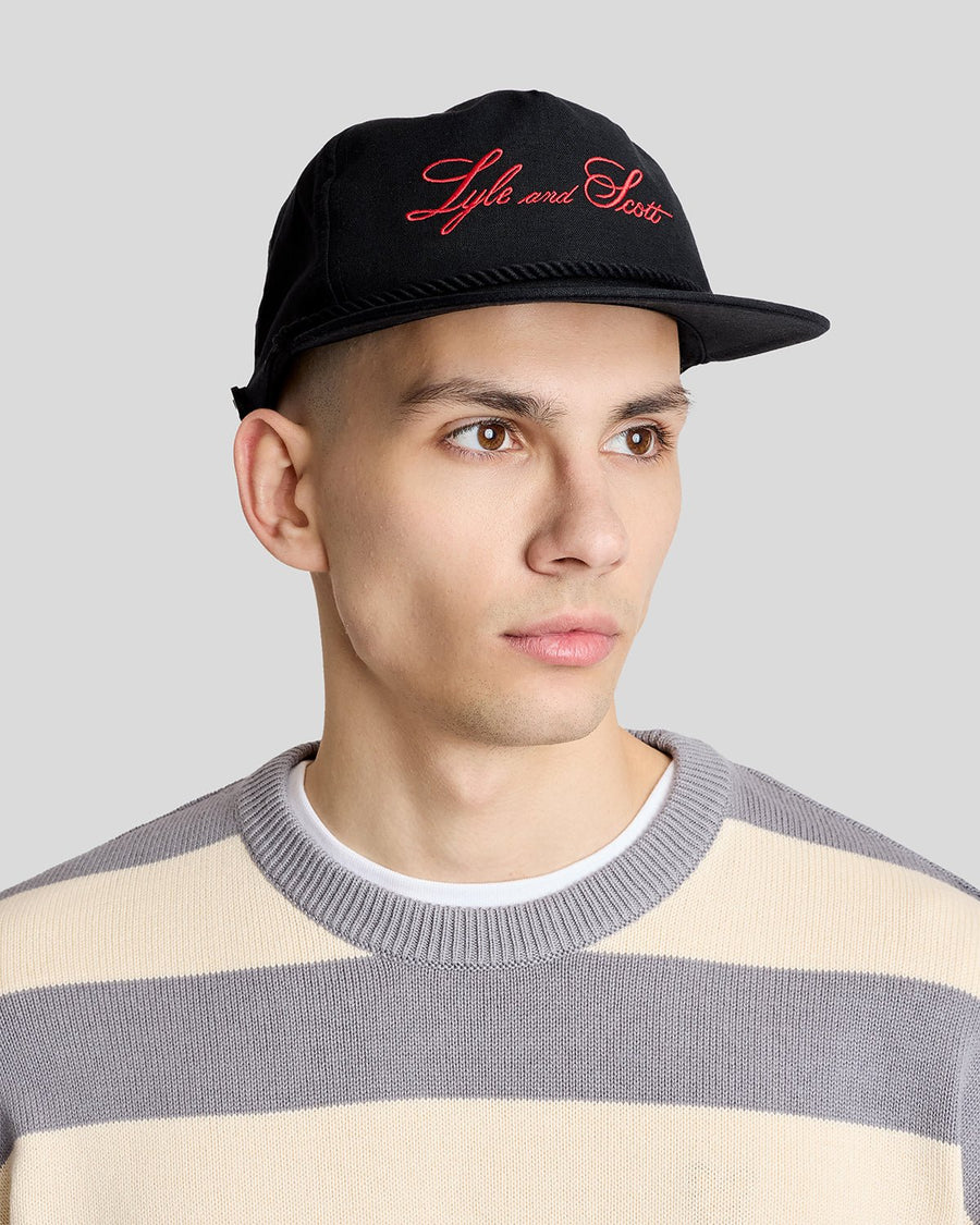 Un homme porte une casquette en toile brodée et cordée, de couleur noire