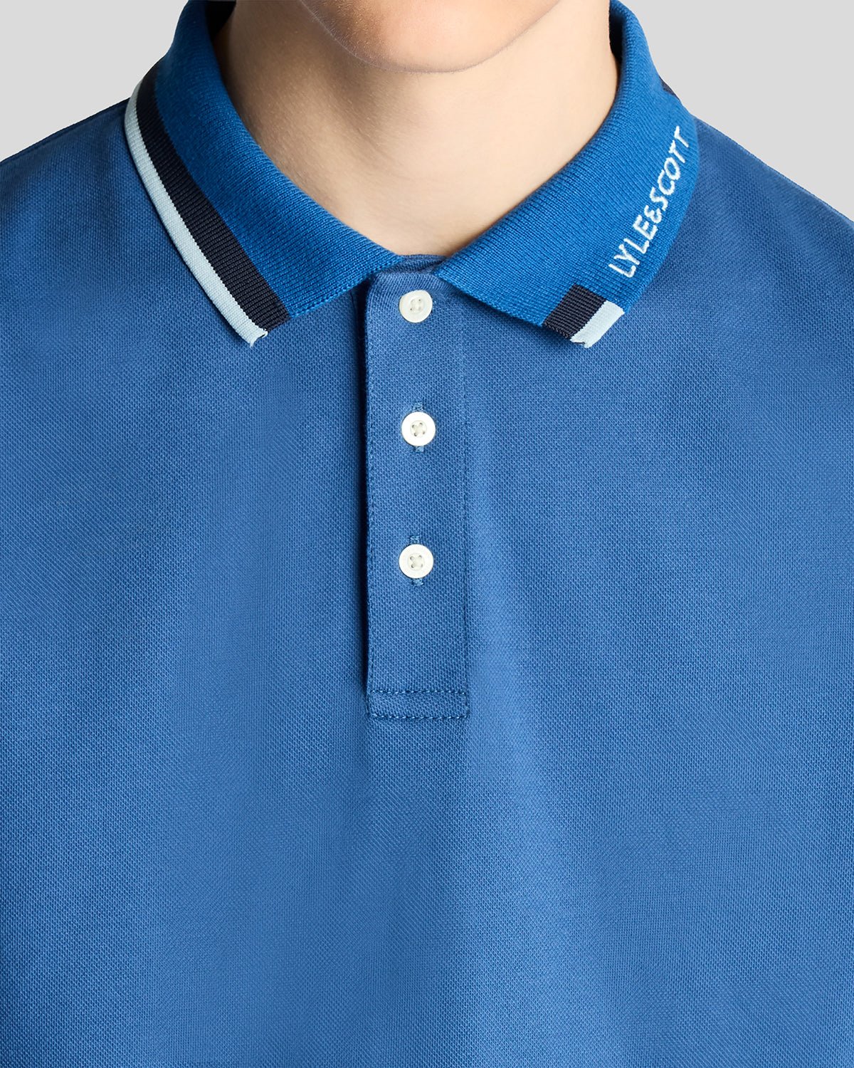 Un homme porte un polo à logo bicolore bleu barbeau foncé