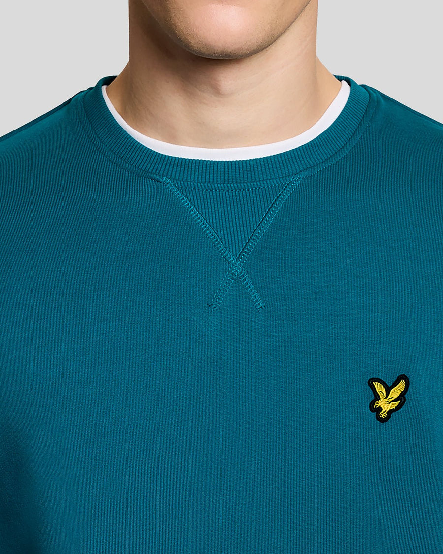 Un homme porte un sweat-shirt à col rond en coton, couleur Lagoon