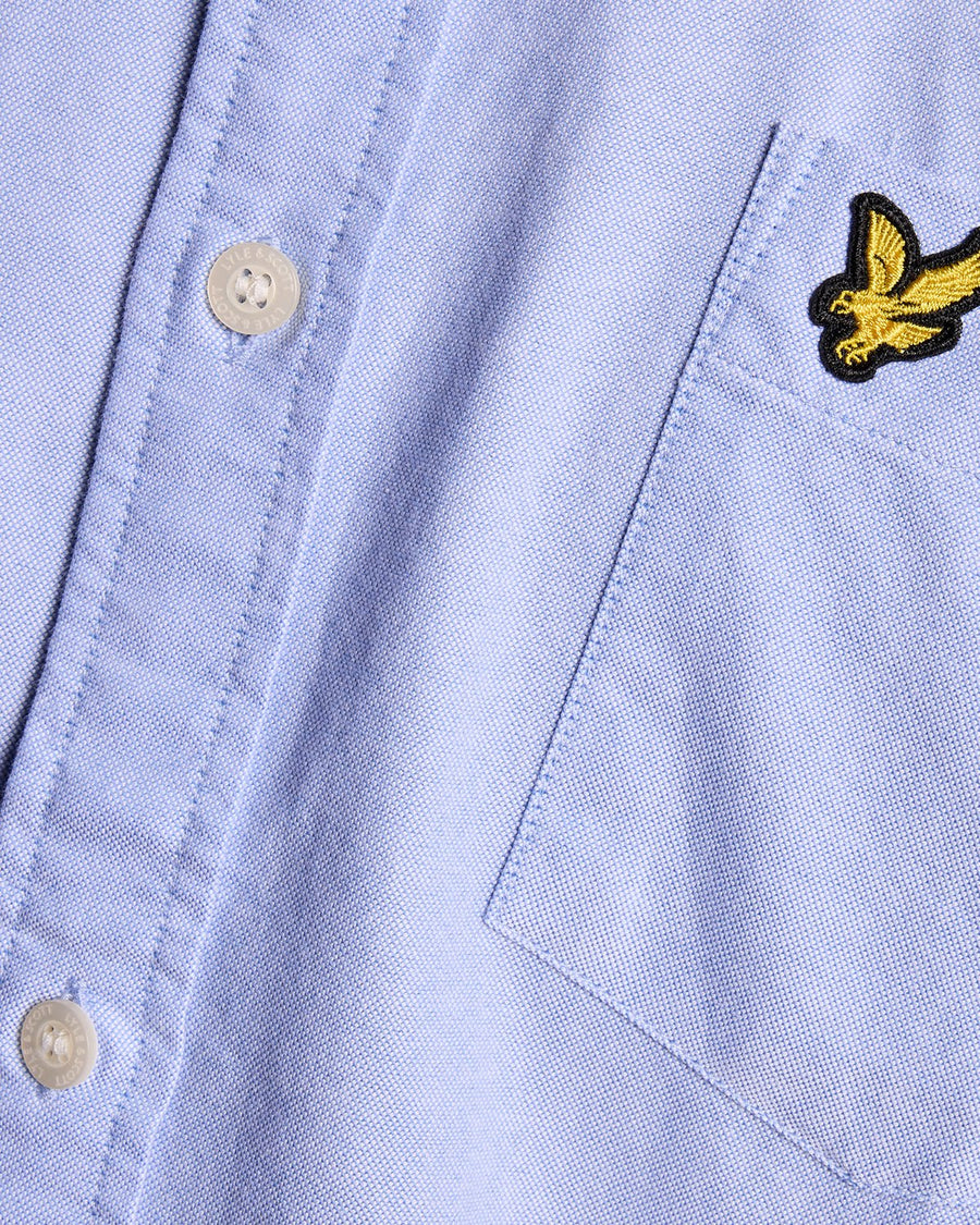 Man wears Cotton Button Down Oxford Shirt in Riviera