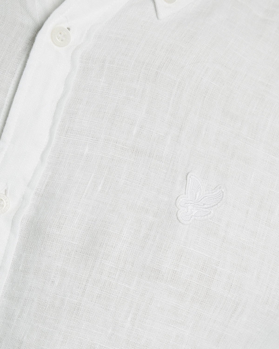 Un homme porte une chemise en lin boutonnée, de couleur blanche