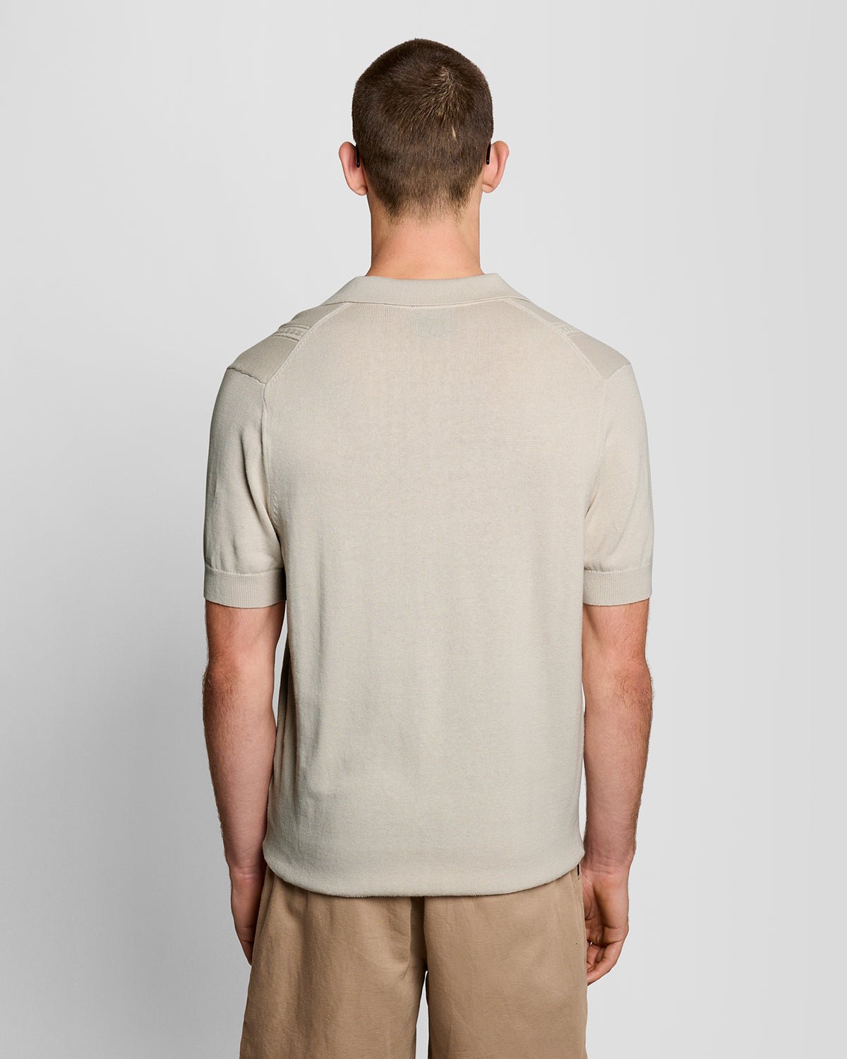 Un homme porte un polo en maille à motif argyle et col ouvert, couleur Cove
