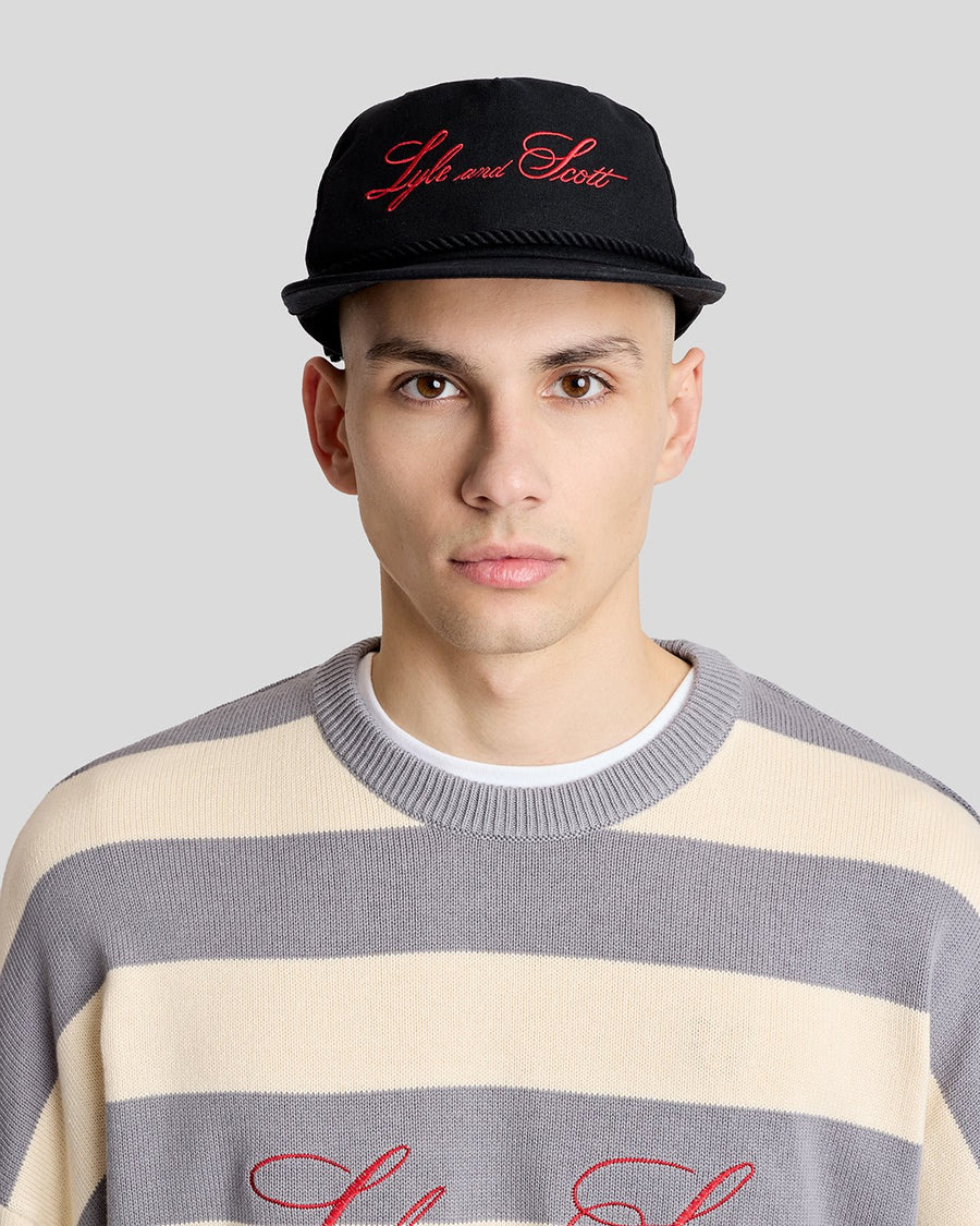 Un homme porte une casquette en toile brodée et cordée, de couleur noire