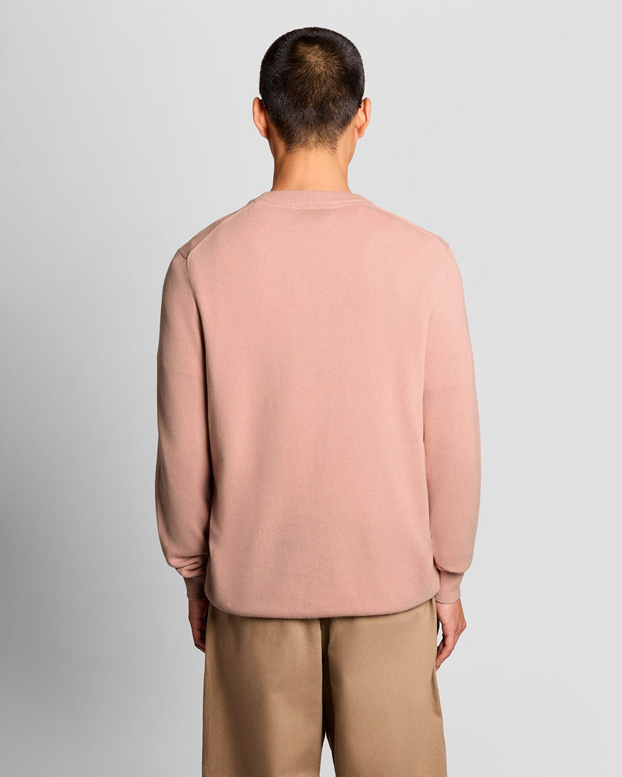 Homme portant un pull à col rond en coton couleur pamplemousse rose