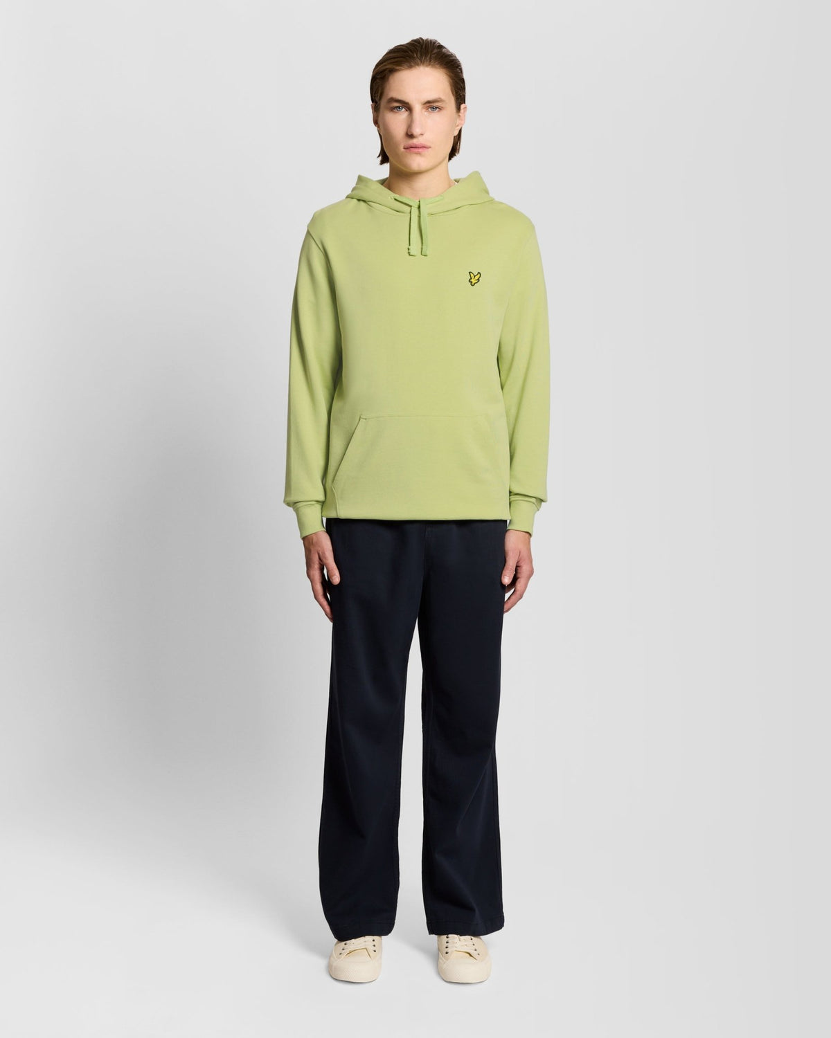 Un homme porte un sweat à capuche Loopback en coton, couleur « Green Grass »