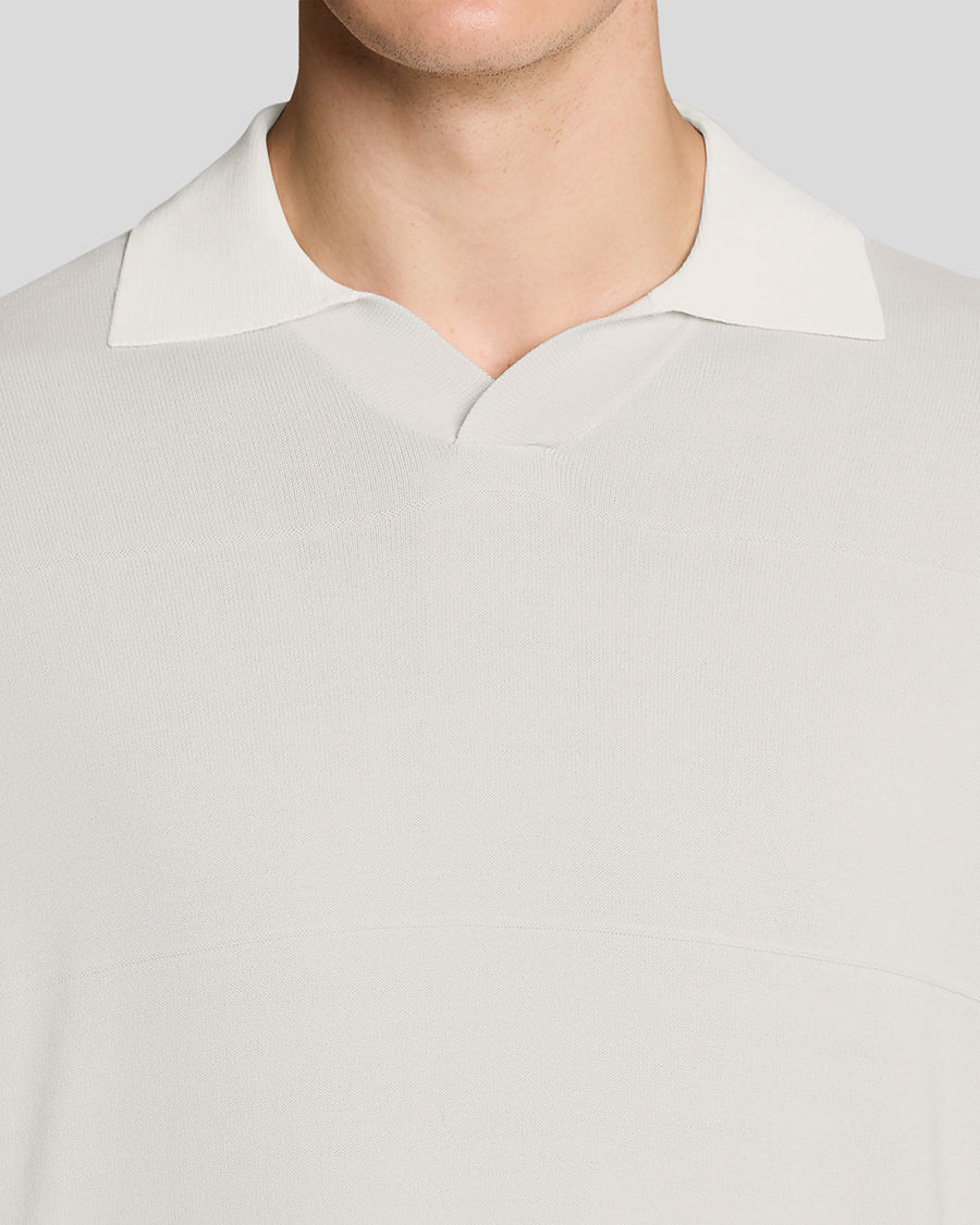 Un homme porte un polo en maille fine à col ouvert, couleur Skylight