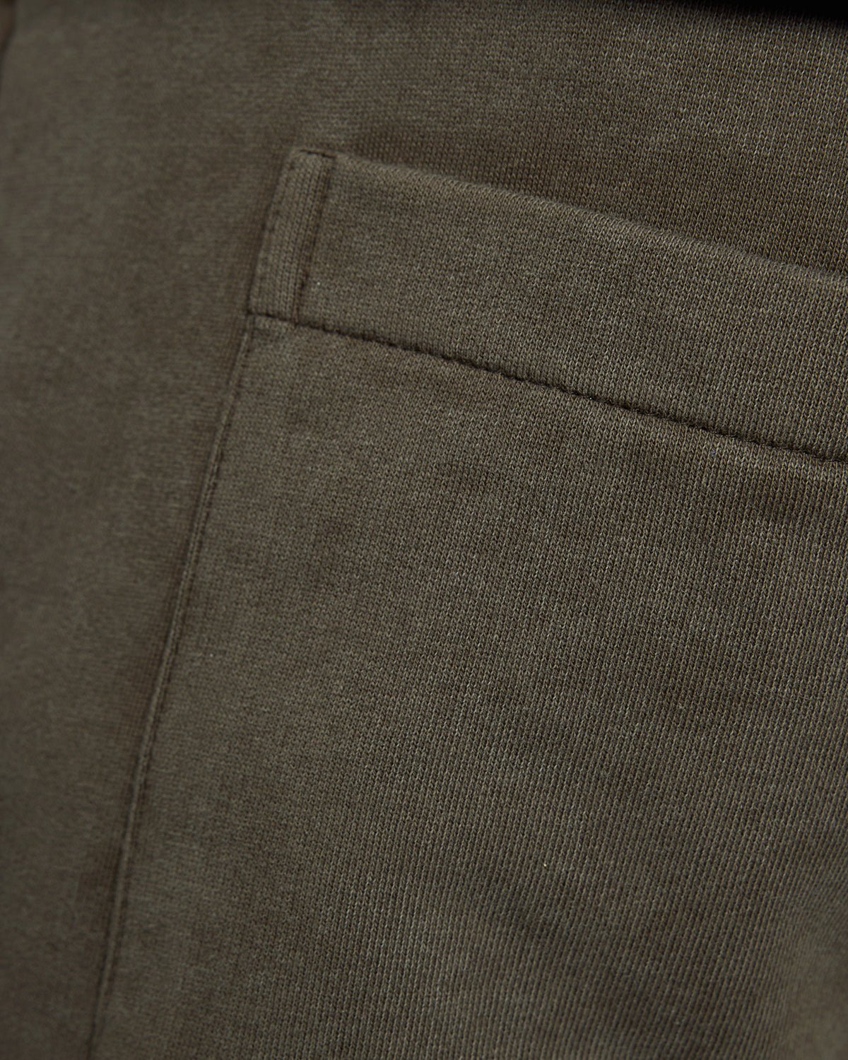 Un homme porte un pantalon de jogging en coton délavé foncé, couleur noir mat