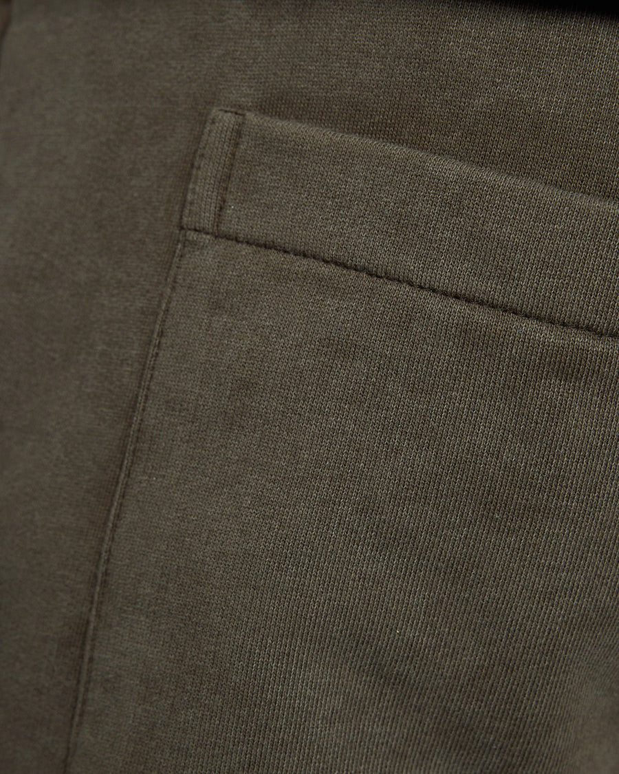 Un homme porte un pantalon de jogging en coton délavé foncé, couleur noir mat