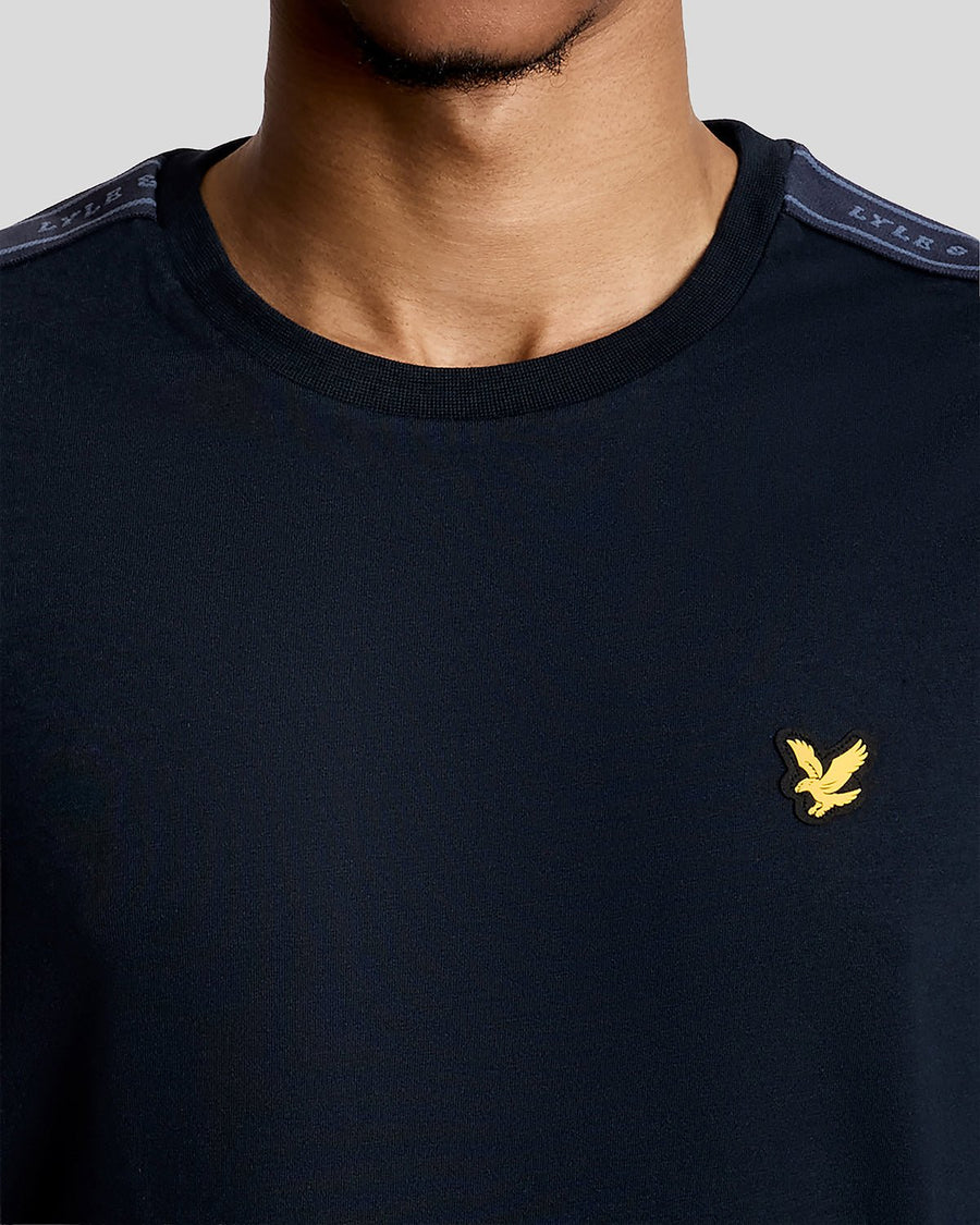 Hombre lleva camiseta deportiva con cinta jacquard en azul marino oscuro.