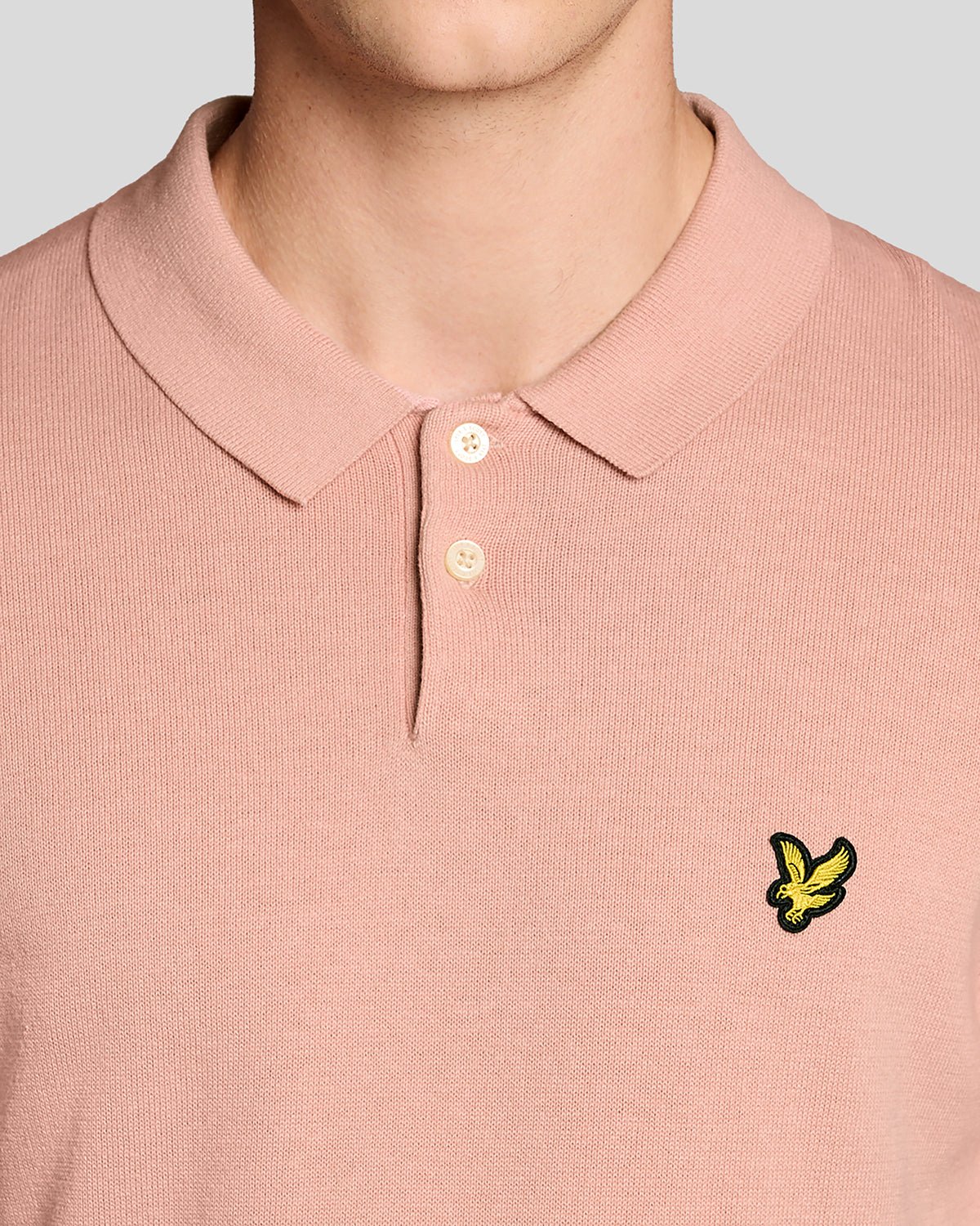 Un homme porte un polo en coton tricoté couleur pamplemousse rose