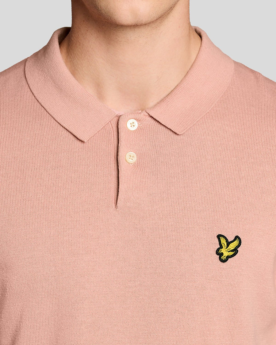 Un homme porte un polo en coton tricoté couleur pamplemousse rose