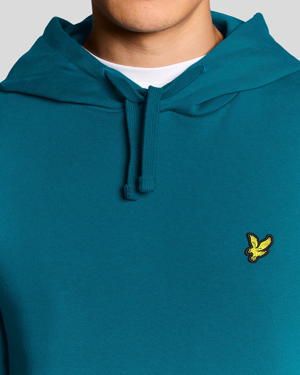 Un homme porte un sweat à capuche en coton Loopback, couleur Lagoon