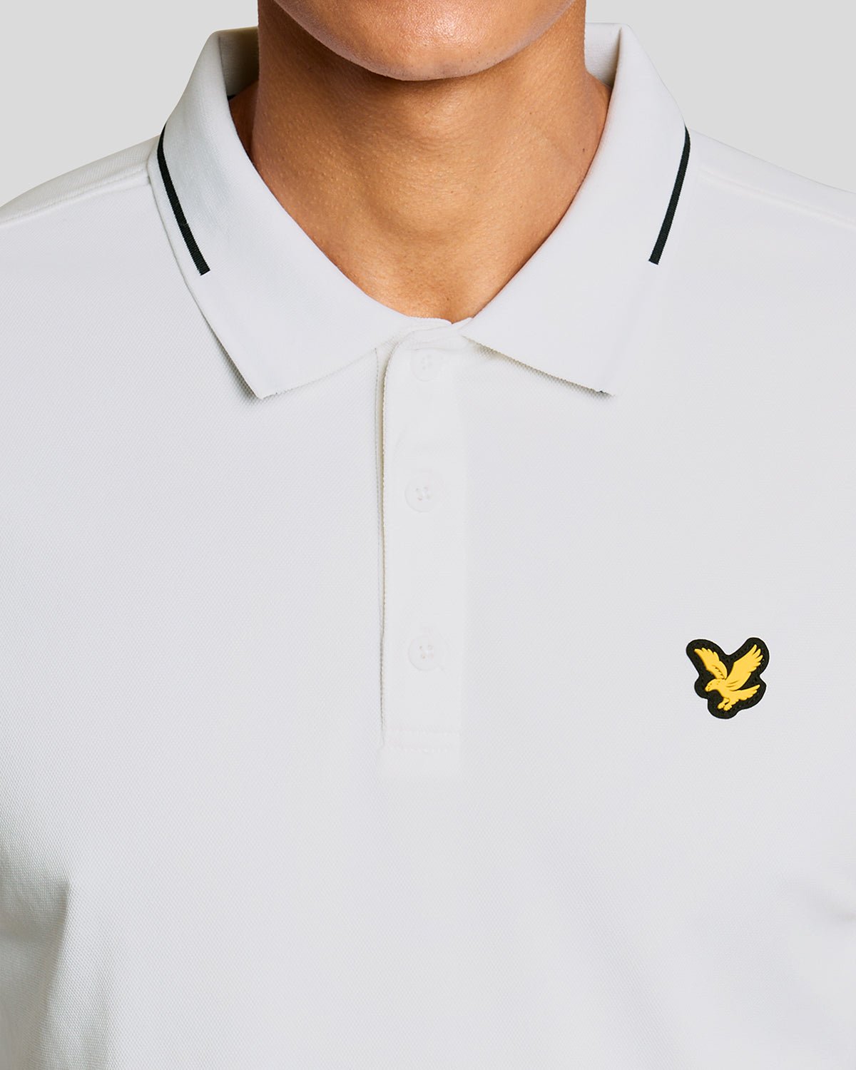 Un homme porte un polo technique à bordures contrastées, de couleur blanche