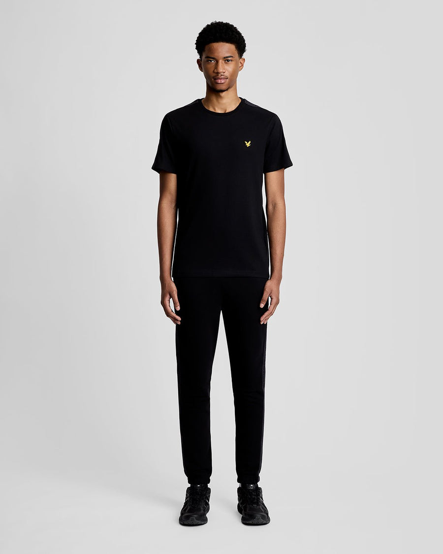 Hombre lleva camiseta deportiva con cinta jacquard en color negro azabache.