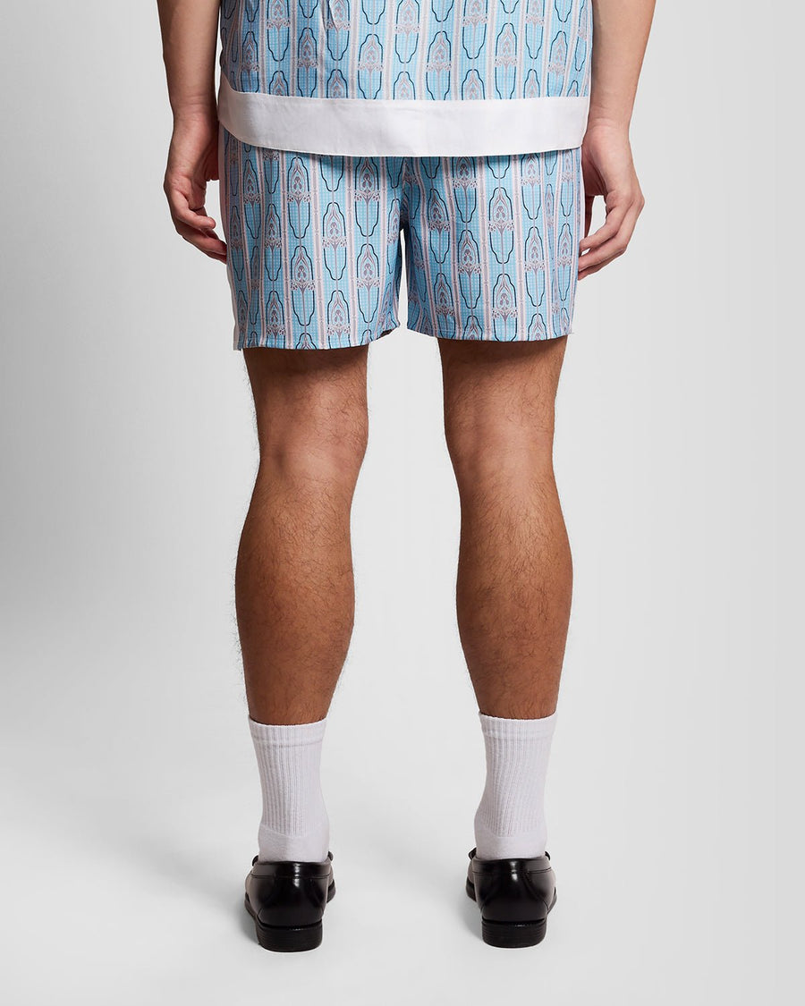Homme portant un short de bain à motifs floraux, couleur crème amande/bleu de Parme