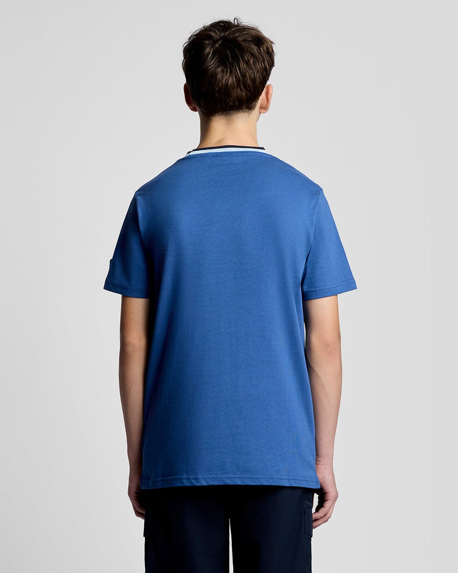 Un homme porte un t-shirt à col rabattu avec logo, couleur bleu barbeau foncé