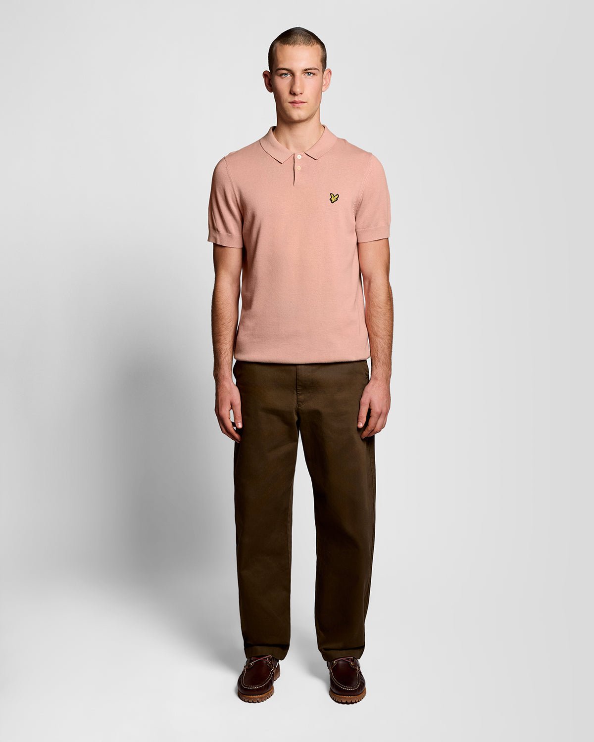 Un homme porte un polo en coton tricoté couleur pamplemousse rose