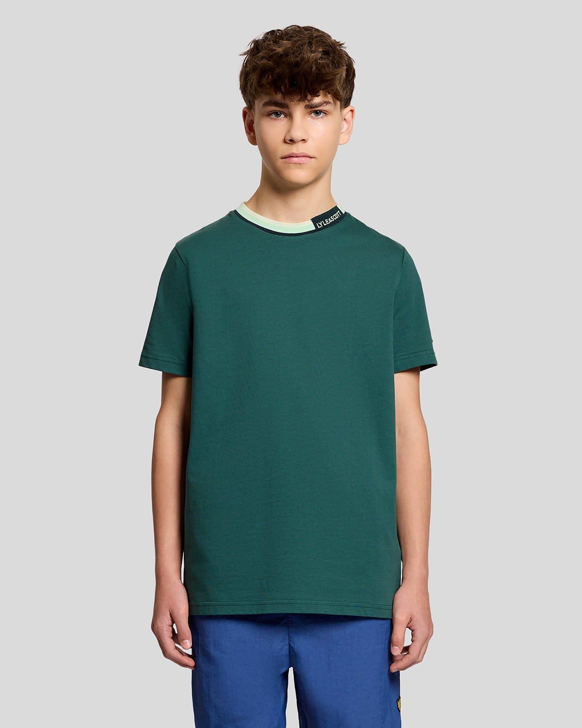Un homme porte un t-shirt à col relevé avec logo, couleur Everglade
