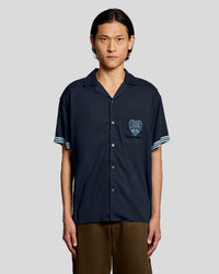 Man wears Short Sleeve Laundry Logo Shirt in Dark Navy/ Chalk Blue