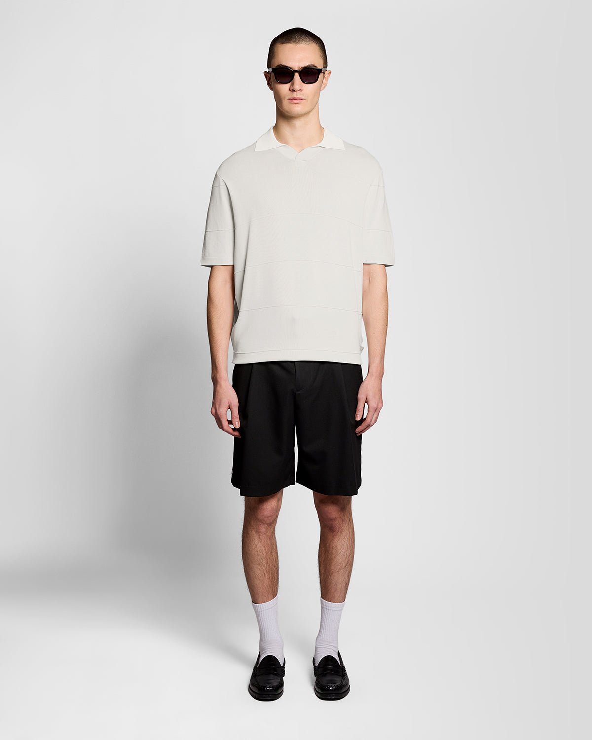Un homme porte un polo en maille fine à col ouvert, couleur Skylight