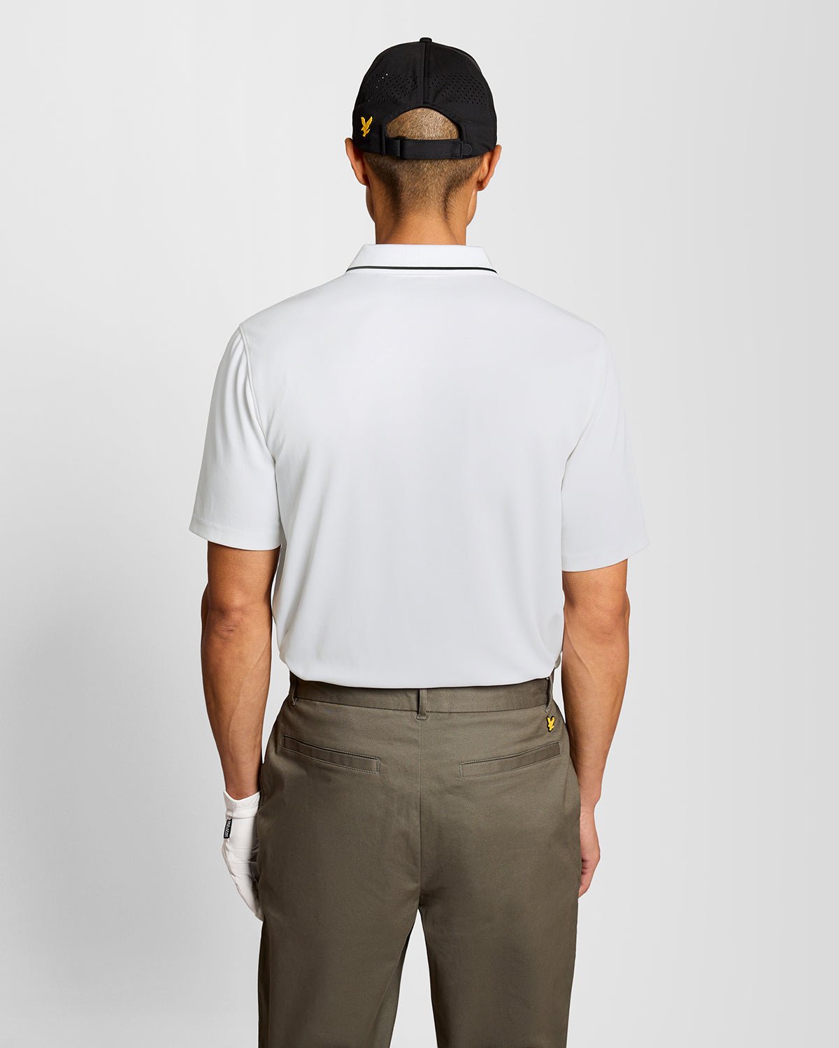 Un homme porte un polo technique à bordures contrastées, de couleur blanche