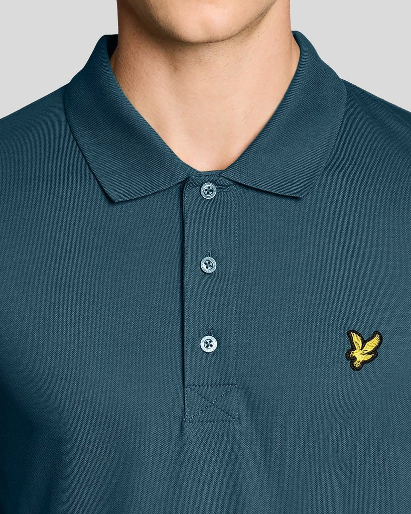 Un homme porte un polo « Everyday Cotton » de couleur bleu sarcelle intense